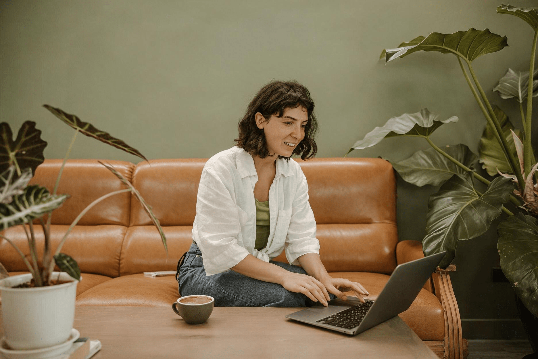 man with dog sitting infront of couch working on laptop